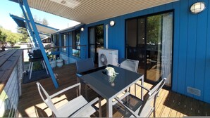 A covered outdoor area with a table and chairs, large windows, and a fan.