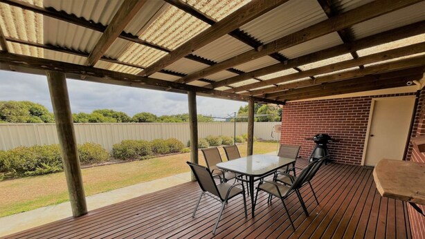 A covered patio with a table and chairs, a grill, and a brick wall. - The Willow in West Beach (Esperance)