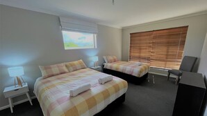 A hotel room with two beds, a desk, a chair, and a window with blinds. - The Willow in West Beach (Esperance)