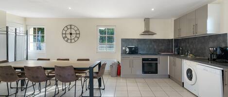 A modern kitchen with a dining area, equipped with appliances like a microwave, oven, and washing machine.