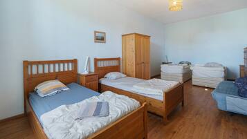 A bedroom with two wooden beds, a wardrobe, and a hanging light fixture.