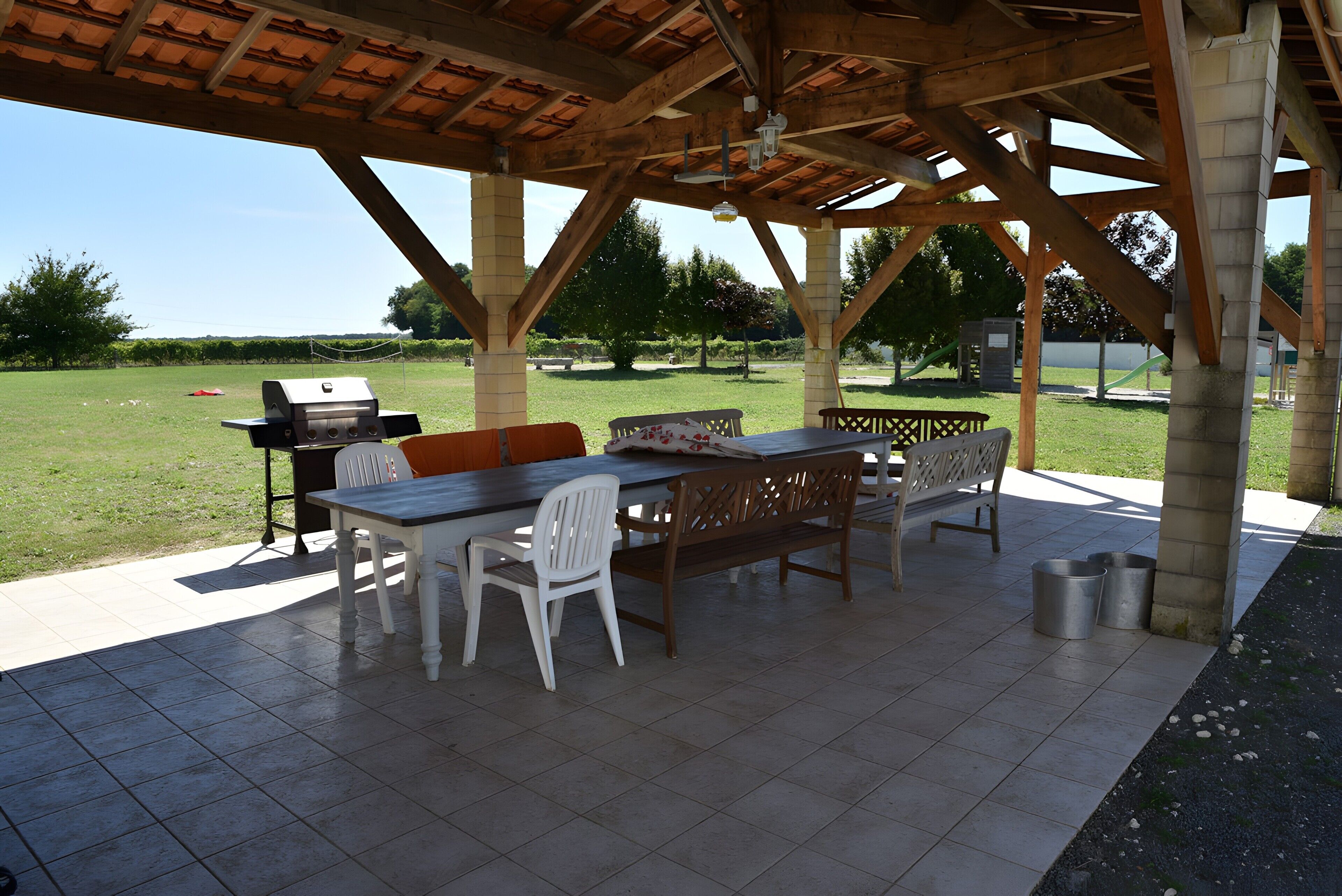 Une terrasse extérieure équipée d’un barbecue, de sièges et offrant une vue sur le paysage environnant.