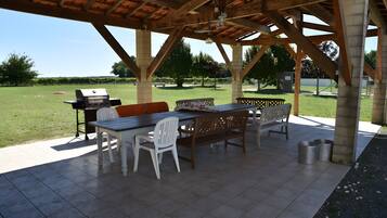 Une terrasse extérieure équipée d’un barbecue, de sièges et offrant une vue sur le paysage environnant.