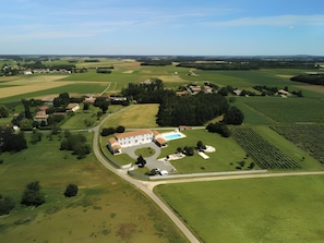 Vista aérea de una finca rural con una construcción grande, campos abiertos y una piscina.