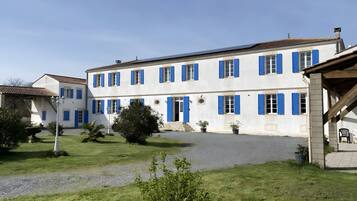 Un bâtiment blanc avec des volets bleus et une allée gravillonnée.