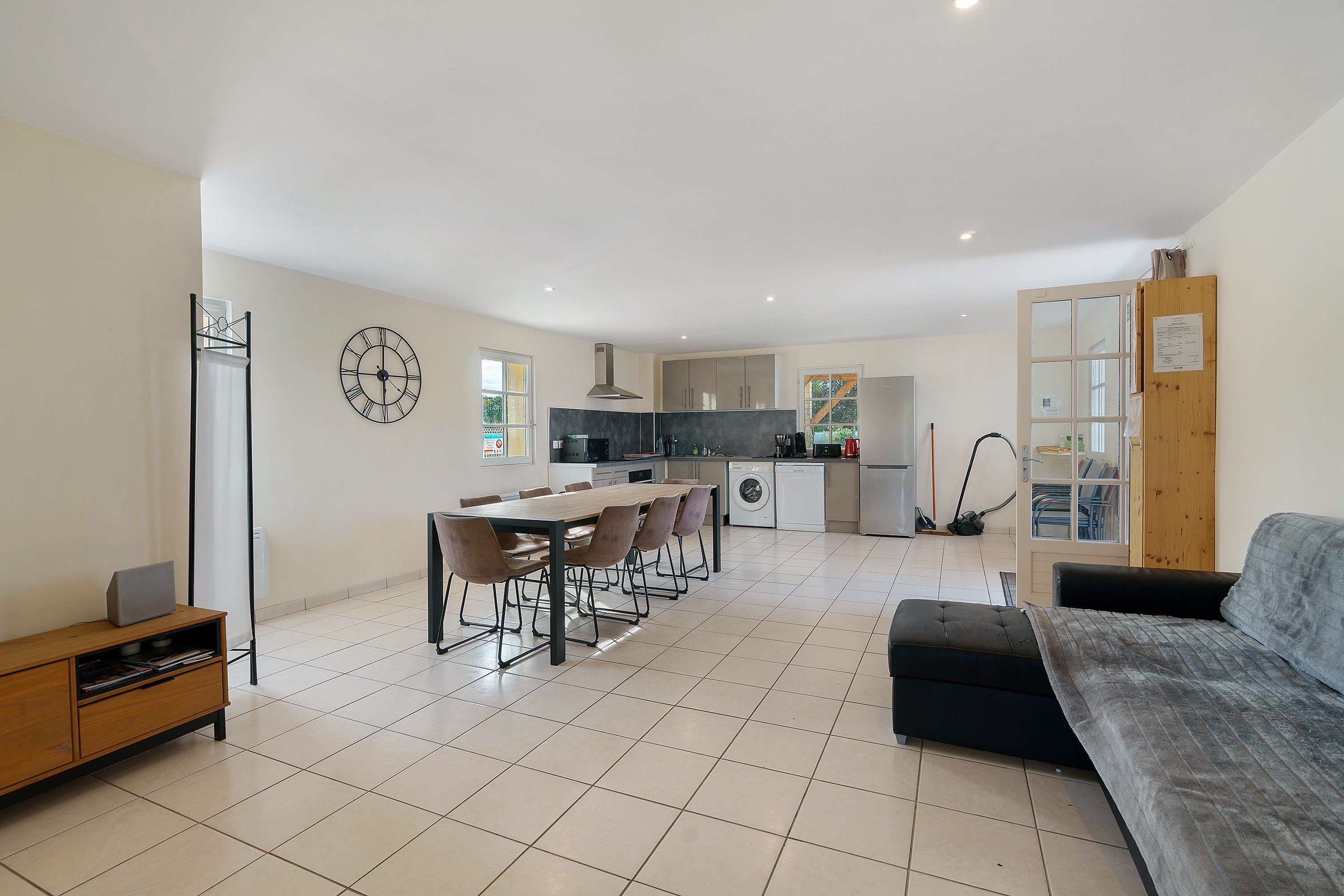 A modern kitchen with a dining area, a sofa, and a small table with chairs.