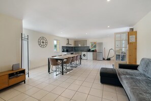 A modern kitchen with a dining area, a sofa, and a small table with chairs.
