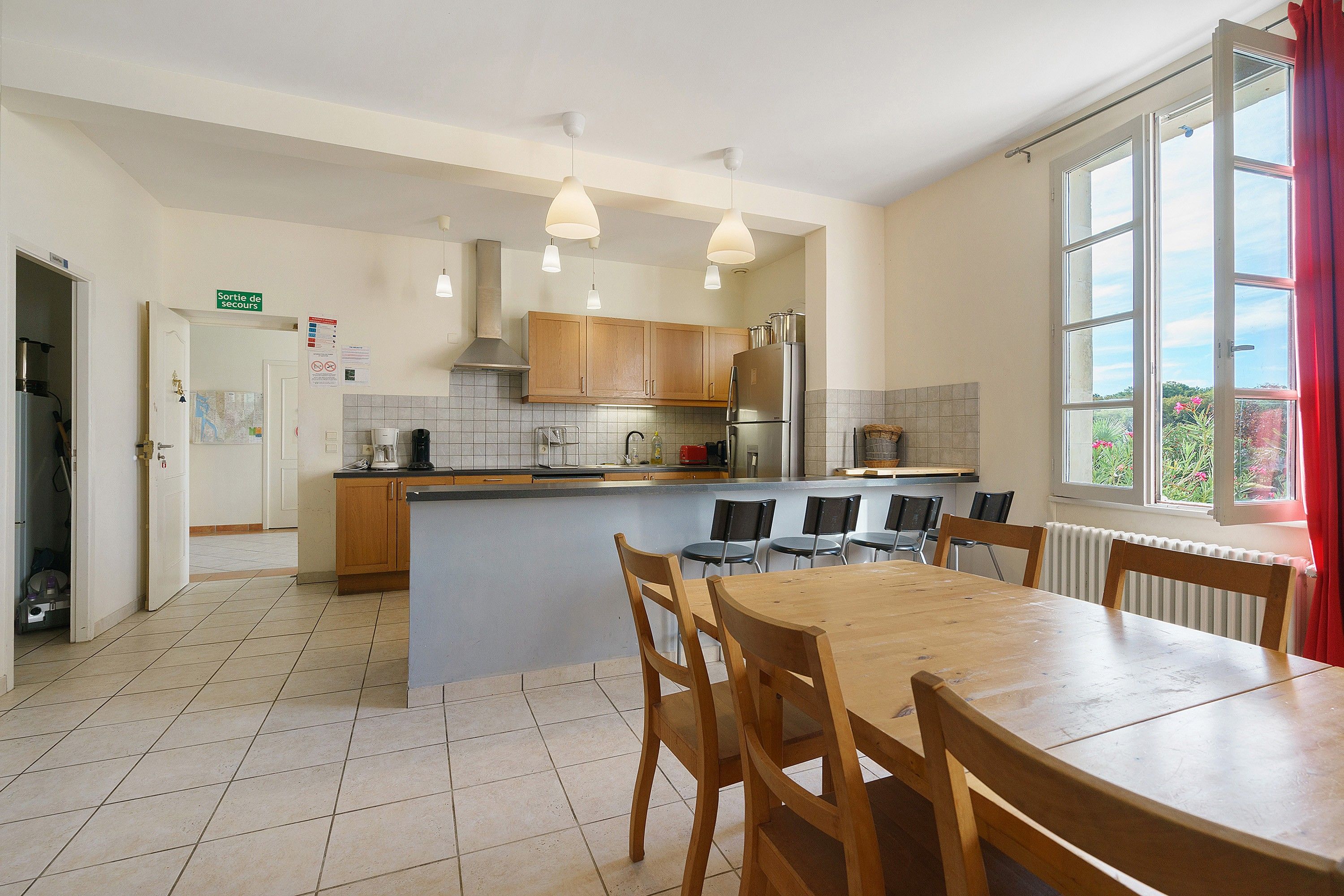 A modern kitchen with wooden cabinets, a central island, and a dining area with a table and chairs.