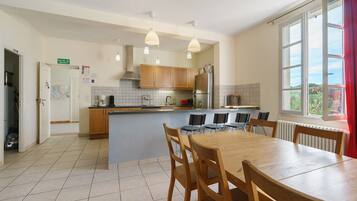 A modern kitchen with wooden cabinets, a central island, and a dining area with a table and chairs.