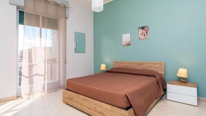A bedroom with a bed, two bedside tables, a window with curtains, and two wall art pieces. - Nicola House (Catania)