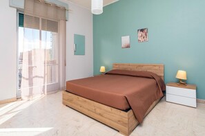 Ein Schlafzimmer mit einem Bett, zwei Nachttischen, einem Fenster mit Vorhängen und zwei Wandbildern.