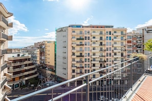 A multi-story residential building with balconies, a pedestrian street below, and a clear sky. - Nicola House (Catania)