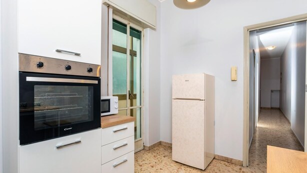 A compact kitchen with a built-in oven, a microwave, and a refrigerator. - Nicola House (Catania)