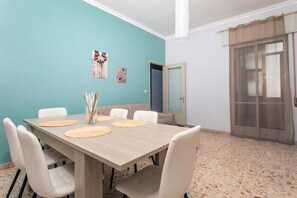 Ein Essbereich mit einem Holztisch, weißen Stühlen und einer wandfarbenen Teal-Wand.