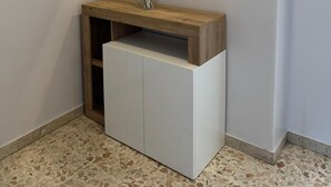 A corner room with a white cabinet, a wooden shelf with a vase, and a wall-mounted mirror. - Nicola House (Catania)