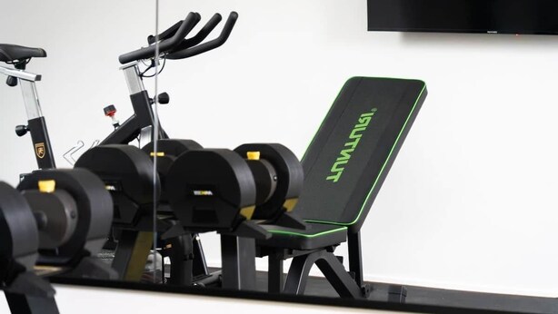 A gym with exercise equipment including a stationary bike, a bench, and weight plates.