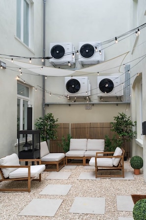 An outdoor seating area with three sofas, a black table, and string lights. - La Savonnière (Bruxelles)