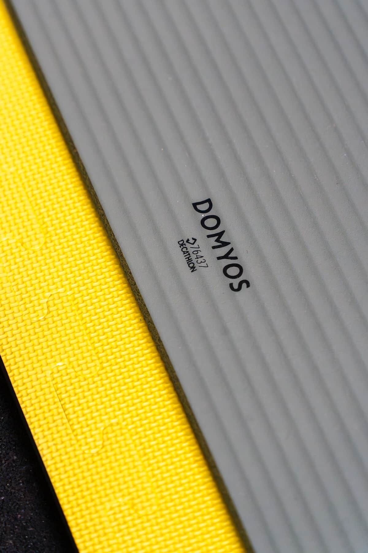 A close-up of a textured surface with the word 'DOMYOS' and a phone number.