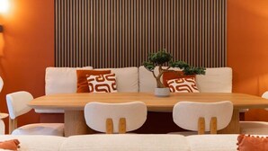 Un comedor con una mesa de madera, sillas blancas y un sofá con cojines estampados.
