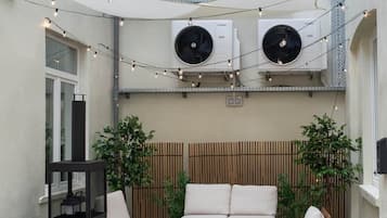 An outdoor seating area with three sofas, a table, and string lights.