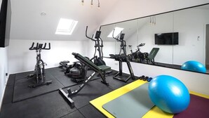 Un gimnasio con equipo de ejercicio, un espejo y una televisión.