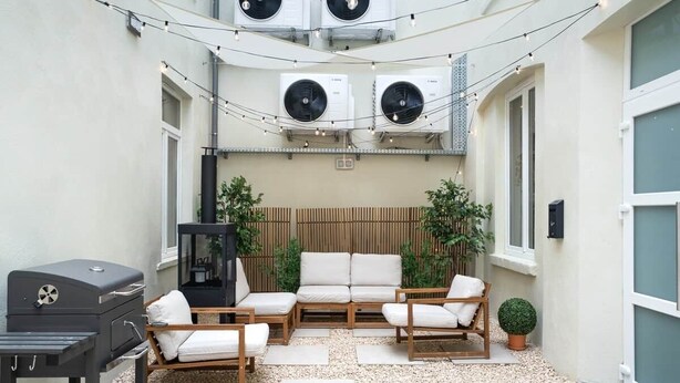 An outdoor patio with a grill, seating area, and air conditioning units. - Chez Thérèse (Bruxelles)