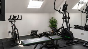 A gym with exercise equipment including a treadmill, stationary bike, and weight bench. - La Notre Dame du Sommeil (Bruxelles)