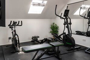 A gym with exercise equipment including a treadmill, stationary bike, and weight bench.