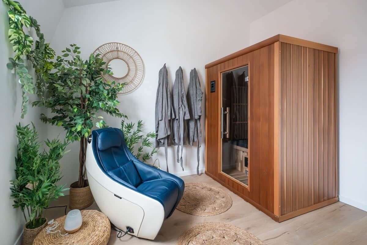 Een kamer met een massagestoel, een houten kast en potplanten.