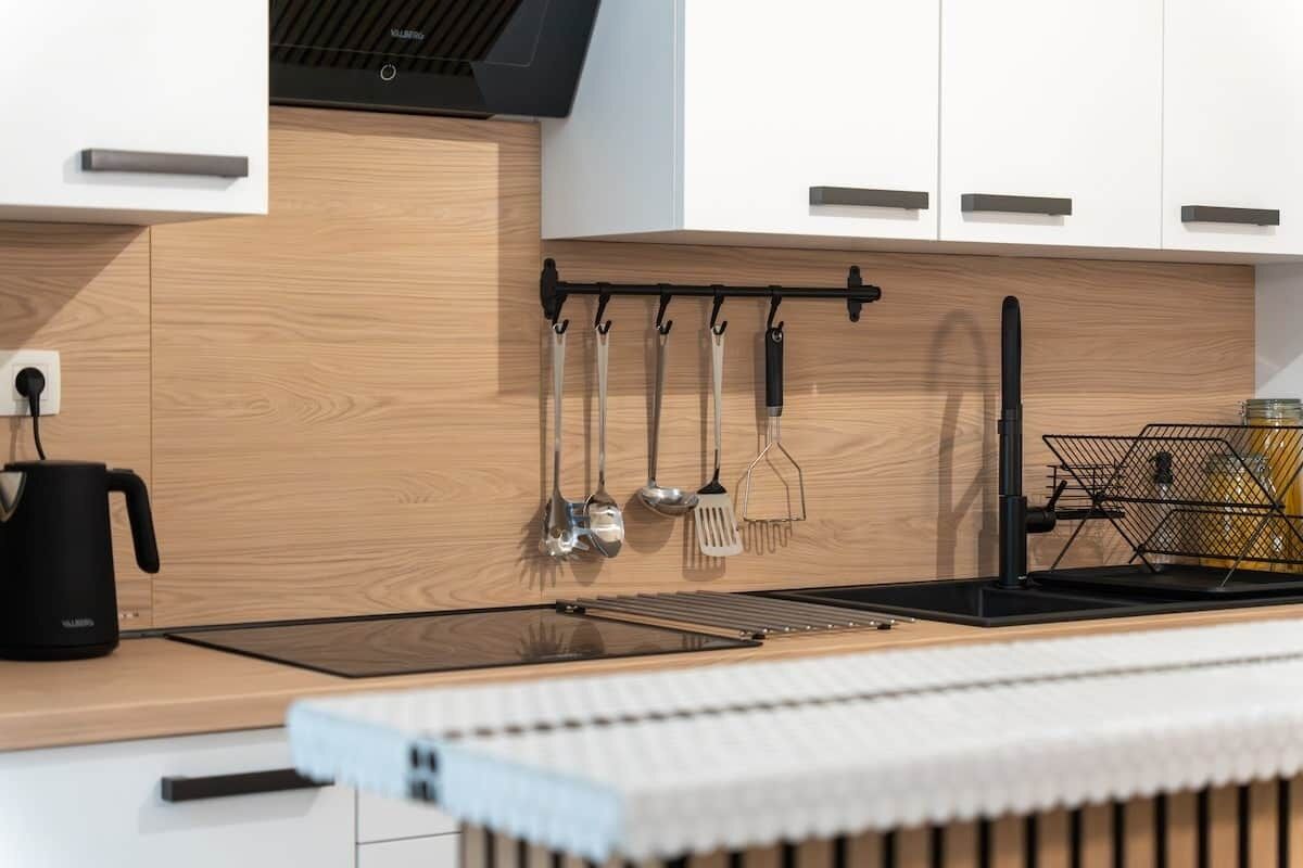 Une cuisine moderne avec un plan de travail en bois, une bouilloire, un porte-ustensiles suspendu et un évier.