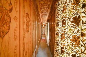 A corridor with ornate wooden paneling and patterned wallpaper, leading to a room with a visible door. - Shahenshah Heritage Houseboat (Srinagar)