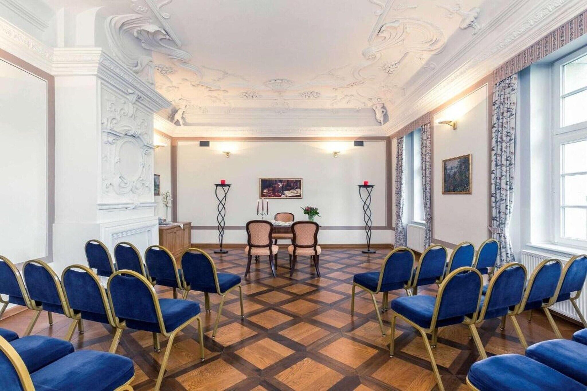 A conference room with a checkered floor, blue chairs, a table, and a painting on the wall.