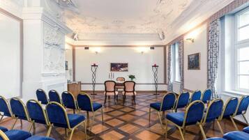 A conference room with a checkered floor, blue chairs, a table, and a painting on the wall.
