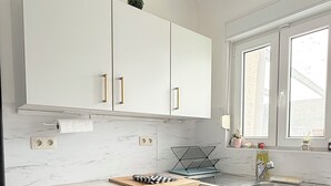 A modern kitchen with white cabinetry, a wooden countertop, a built-in sink, and a window providing natural light. - Cosy House for 10 with clim and garden (Nivelles)