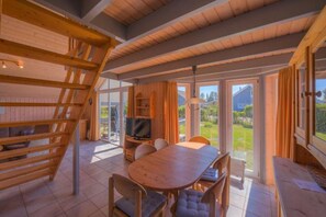 Ein Holzinnenraum mit Essbereich, Fernseher und Blick ins Freie.
