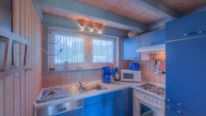 A compact kitchen with a sink, stove, and microwave. - Ferienhaus im skandinavischen Stil mit Garten im Hafendorf Müritz (Rechlin)