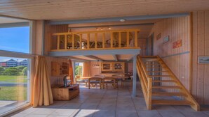 A spacious interior with a high ceiling, a wooden staircase, and a dining area. - Ferienhaus im skandinavischen Stil mit Garten im Hafendorf Müritz (Rechlin)