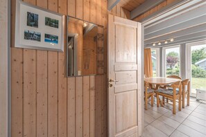 A wooden-paneled room with a dining table and chairs, a framed picture on the wall, and a door leading to another area. - Gemütliches Ferienhaus mit Garten und Terrasse im Hafendorf Müritz (Rechlin)