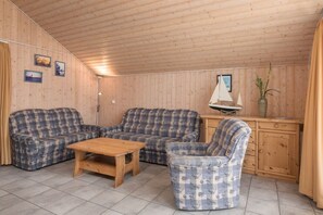 Eine Holzhütte mit Holzwänden und -decke, zwei Sofas, einem Holztisch, einem kleinen Schrank und einem Modell eines Segelboots.