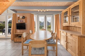 Eine moderne Küche mit Holzschränken, einem Esstisch, Stühlen und einem Fernseher.