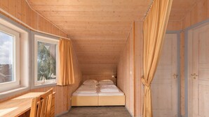 Una habitación tipo cabaña de madera con cama, escritorio y ventana.