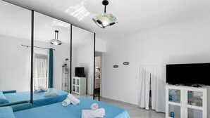 Une chambre d’hôtel avec deux lits, une télévision, une armoire et une salle de bain visible à travers une porte ouverte.