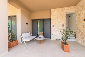 A modern outdoor seating area with a sofa, chairs, and a small table. - Aetherion Suites (Chania)
