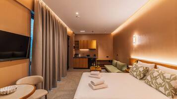 Une chambre d’hôtel comprenant un lit, une télévision, un bureau, une chaise, un canapé et une kitchenette.