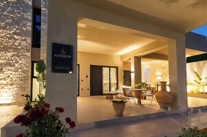 Fachada moderna de un edificio con un cartel que dice 'AETHERION BOUTIQUE LIVING'.