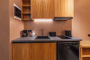 Una cocina compacta con armarios de madera, un lavaplatos empotrado, lavavajillas y una cafetera.