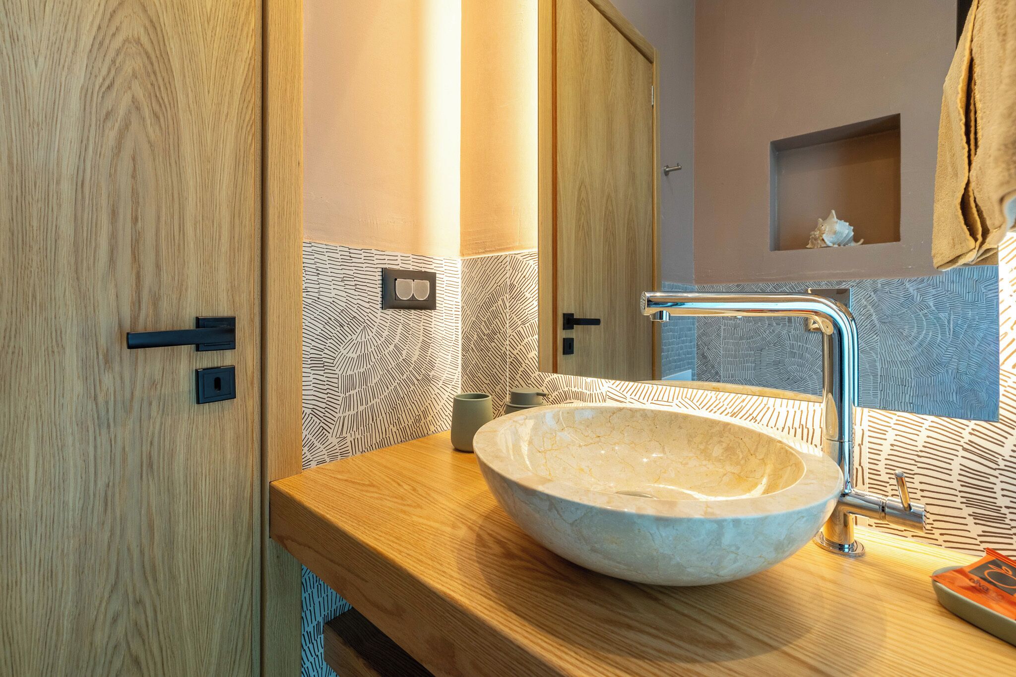 A bathroom with a wooden vanity, a vessel sink, and a mirror.