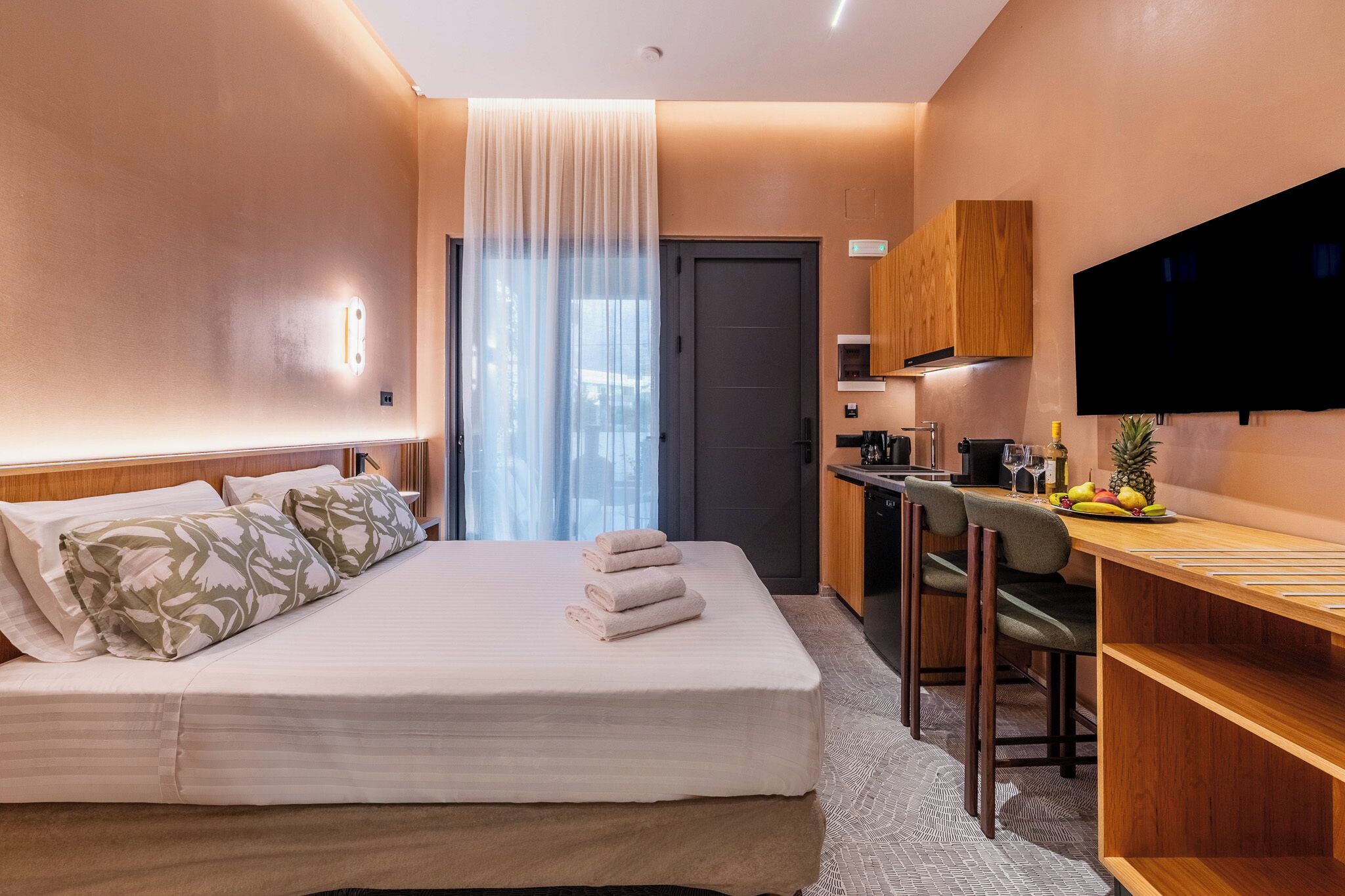 Una camera d'albergo con un letto, una scrivania, una televisione e una porta.