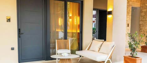 A modern outdoor seating area with a table and two chairs, a sliding glass door, and a stone wall.