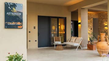 A modern outdoor seating area with a sofa and chairs, a large vase, and a sign for Aetherion Apartments.